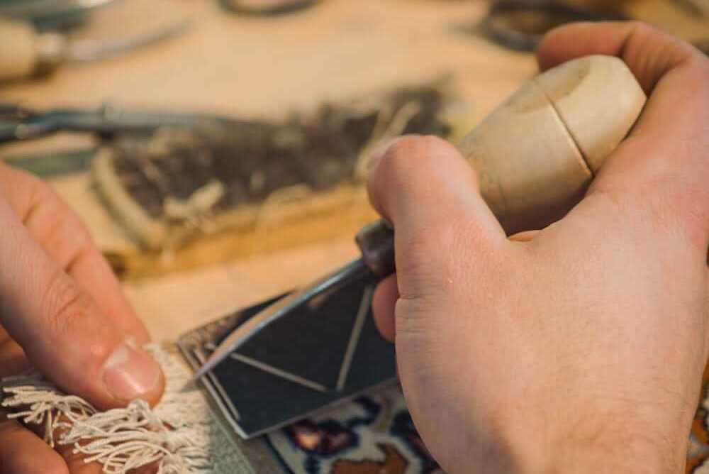 Dettaglio del restauro artigianale di un tappeto persiano