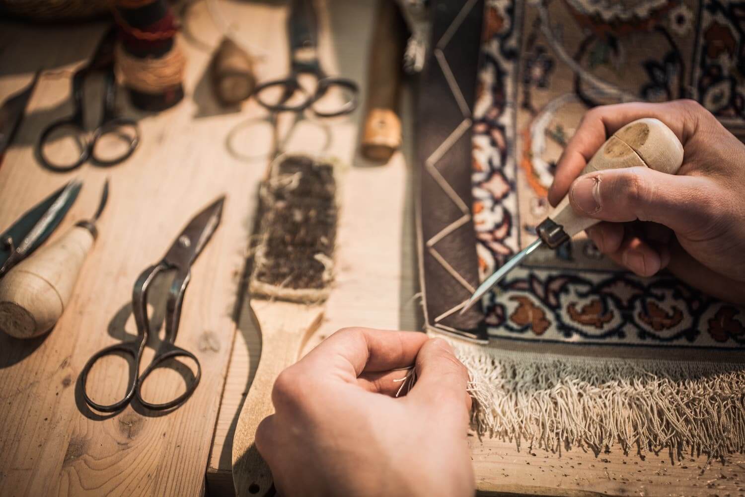 Artigiano al lavoro sul restauro di un tappeto orientale